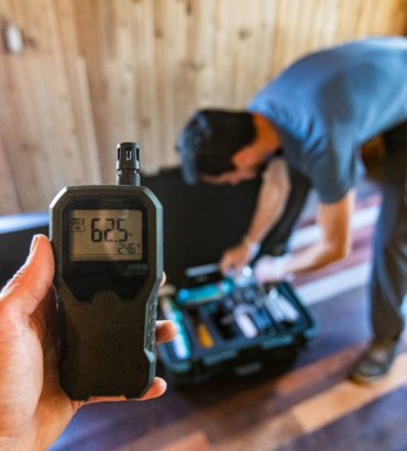 A first person perspective of a person using an indoor air quality monitor device, checking for allergens, particles and CO2 during a domestic home inspection.